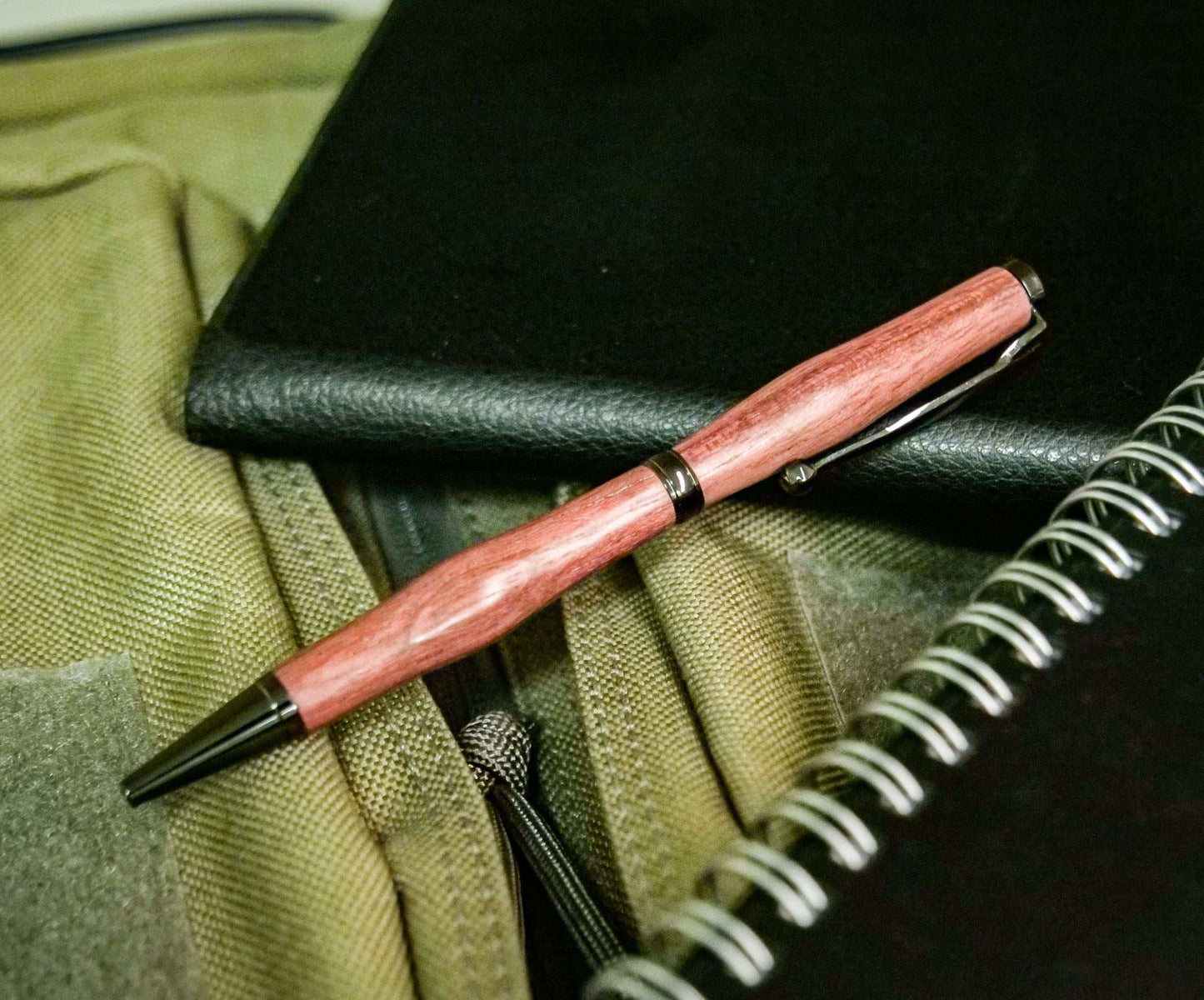 Handmade twist pen with purpleheart wood and gunmetal hardware on green fabric with notebooks